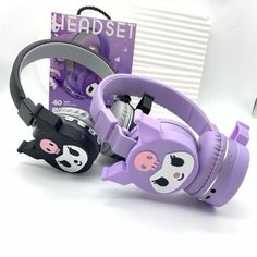 purple headphones with black and white cat faces on them, sitting next to a box