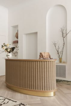 a white and gold reception area with flowers on the counter, vases in the background