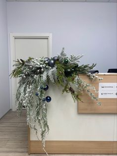 an office cubicle decorated for christmas with greenery and baubles hanging from the wall