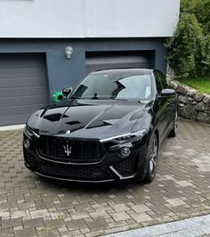 a black masera parked in front of a garage