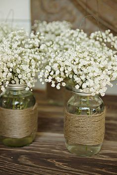 two vases filled with baby's breath flowers on top of a wooden table