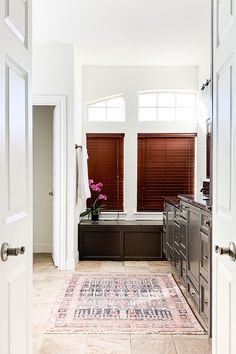 an entry way leading to a kitchen with two windows and a rug on the floor