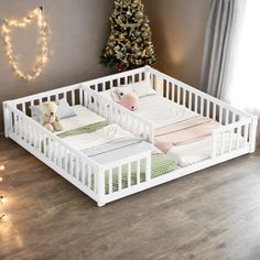 two baby cribs sitting in front of a christmas tree