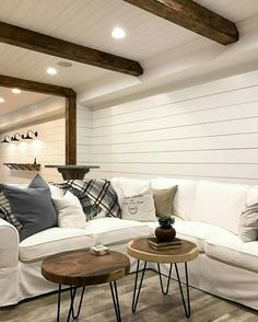 a living room with white couches and pillows on top of the sofa, along with two end tables