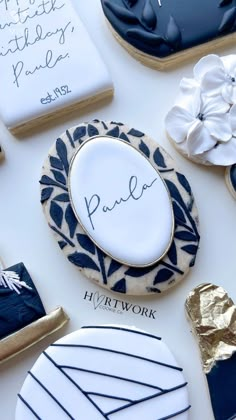 cookies decorated with royal blue and white icing are displayed on a table, surrounded by handwritten greetings