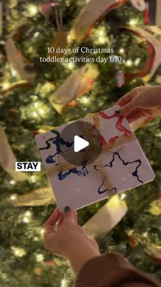 someone holding up a christmas card in front of a tree