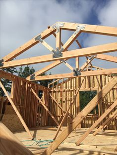 a house being built with wooden framing and roof trusses on the top half of it