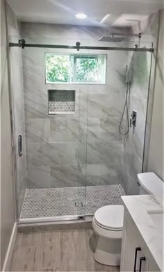 a walk in shower sitting next to a toilet and a sink with a window above it