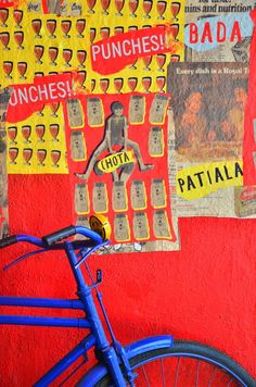 a blue bike parked against a red wall with posters on it's side and the words punches hot in spanish