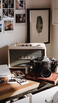 an old fashioned camera sitting on top of a wooden table next to a wall with pictures