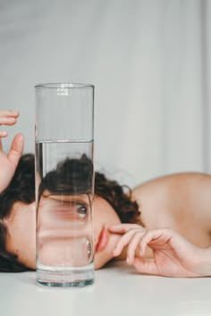 a woman laying down next to a glass of water