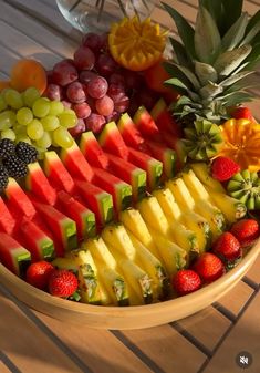 a bowl filled with lots of different types of fruit on top of a wooden table