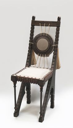 a chair made out of wood and rope with a circular design on the back, sitting in front of a white background