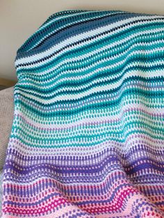 a crocheted blanket that has been made to look like an ocean wave