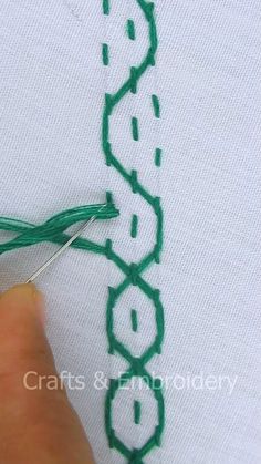 someone is stitching on the back of a t - shirt with green thread and scissors