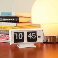 an alarm clock sitting on top of a wooden table next to a stack of books