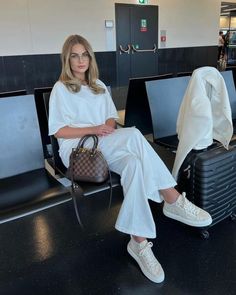 a woman sitting in an airport with her luggage