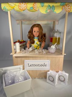 a doll is sitting at a lemonade stand