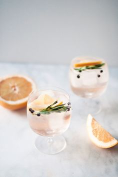 two glasses filled with lemonade and rosemary garnish on top of a marble table