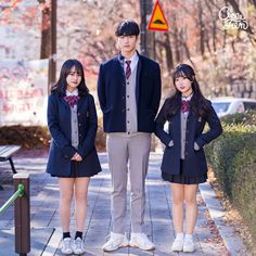 three young people standing next to each other on a sidewalk