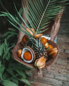 a person holding a wooden bowl filled with fruit