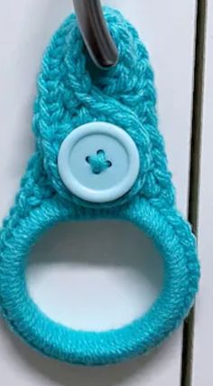 a blue crocheted cell phone holder with a button