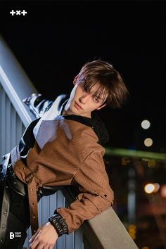 a young man leaning against a railing with his hand on his hip