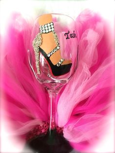 a wine glass with a shoe on it and pink tulle around the bottom,