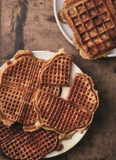 some waffles are on a white plate and one is cut into heart shapes