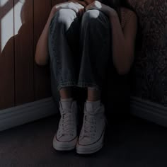 a person sitting on the floor with their feet up in front of a wall and shadows coming from them