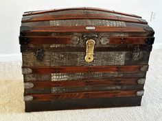 an old trunk is sitting on the floor in front of a white carpeted wall