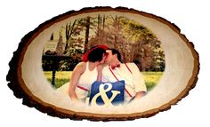 a couple kissing in front of a tree slice with the word & amp on it