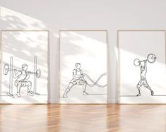 three framed drawings of people doing different things on the wall in a room with wood flooring