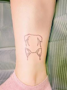 a small tattoo on the ankle of a woman's lower leg with a dog head