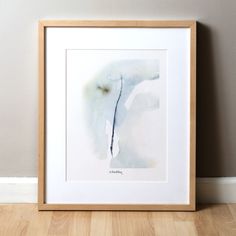 a watercolor painting in a wooden frame on the floor next to a white wall