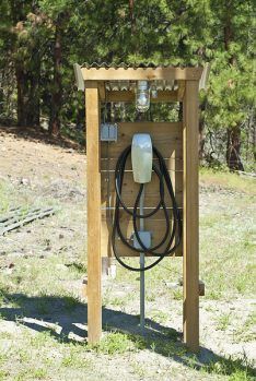 an electric charger attached to a wooden box in the middle of a grassy field