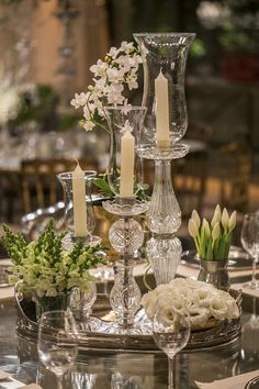 a table topped with lots of glass vases filled with flowers