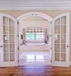 an open door leading to a bathroom with a tub in the center and windows on both sides