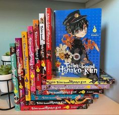 a stack of children's books sitting on top of a wooden table next to a potted plant