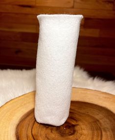 a tall white vase sitting on top of a wooden table next to a pile of fur