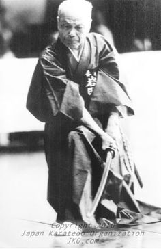 an old black and white photo of a man in a kimono holding a cane