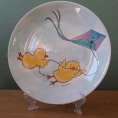 a plate with two little yellow chicks flying a kite on it's side,