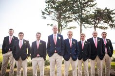 a group of men standing next to each other wearing suits and ties on the grass