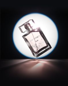 a bottle of cologne sitting on top of a table in front of a blue light