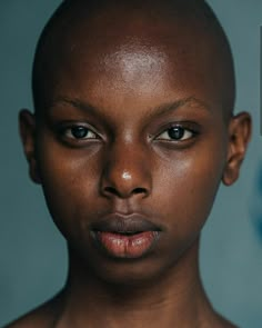 a close up of a person with a bald head and blue eyes looking at the camera