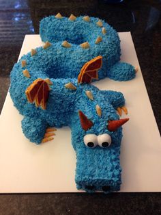 a cake shaped like a blue dragon sitting on top of a table