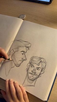 a person drawing faces on paper with a pen and pencil in front of the image