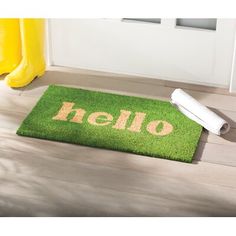 a green door mat with the word hello on it next to a yellow rubber roller