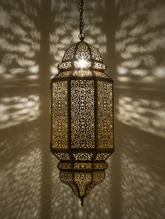 a lamp hanging from the ceiling in a room with shadows on the wall behind it