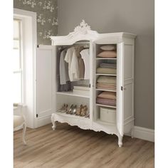 a white armoire with clothes and shoes on it